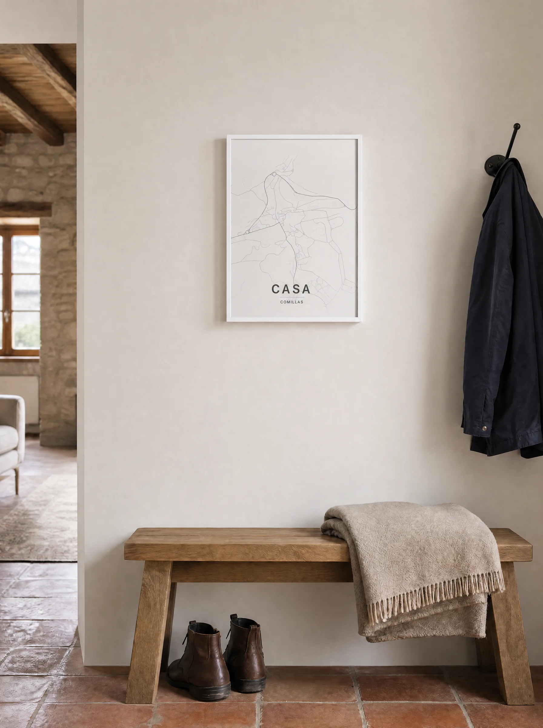 Mapa de Comillas titulado “Casa”, 30x40 cm con marco blanco, en el recibidor de una casa de piedra